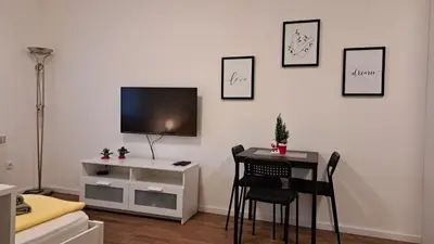 a room with a table and a tv on a wall at Apartment Sanja in Belgrade