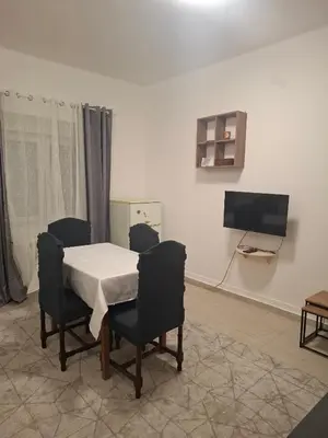 a dining room with a table and chairs and a television at Paviljoni apartman in Tošin Bunar