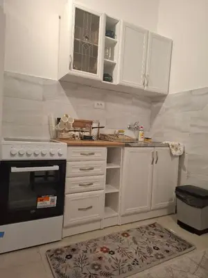 a kitchen with white cabinets and a stove at Paviljoni apartman in Tošin Bunar