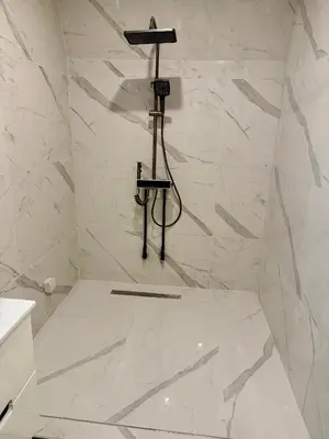 a bathroom with a shower with white marble walls at Luxure Suites in Belgrade