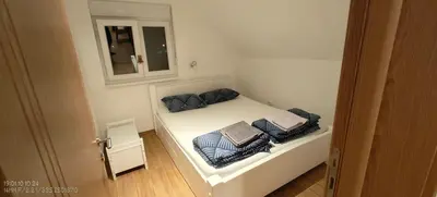 a small bedroom with a white bed with blue pillows at Dušan in Beograd