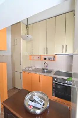 a kitchen with orange cabinets and a wooden table at Botanical Hideout - Near Botanical Garden & City Center in Belgrade