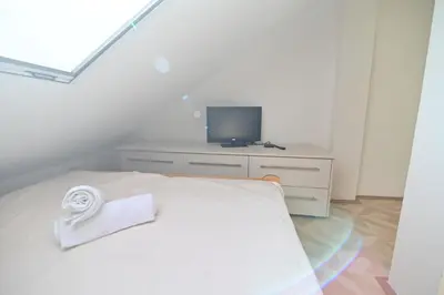 a white bedroom with a bed and a tv at Botanical Hideout - Near Botanical Garden & City Center in Belgrade