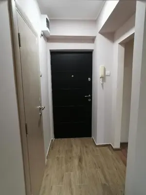 a hallway with a black door and a wooden floor at Vojvoda Apartment in Belgrade