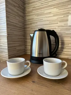 two cups on plates next to a tea kettle at Vojvoda Apartment in Belgrade