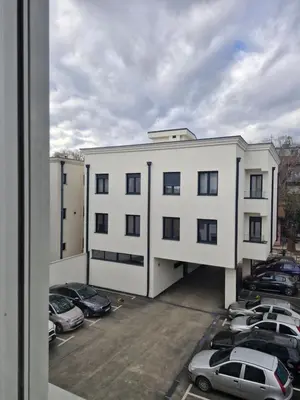 a white building with cars parked in a parking lot at Kolet Zemun in Belgrade