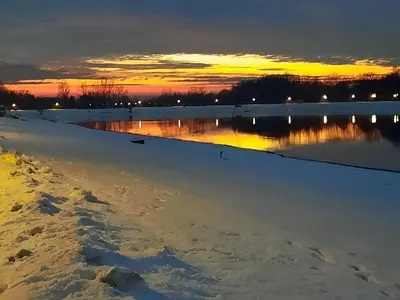 a sunset over a snow covered lake with the sun setting at Pogled Ada 1 in Belgrade