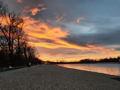 a person walking on the shore of a lake at sunset at Pogled Ada 1 in Belgrade