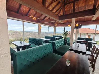 a restaurant with green booths and tables and windows at Vinogradi Zmajevački in Mladenovac