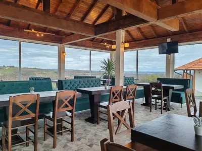 a restaurant with tables and chairs and windows at Vinogradi Zmajevački in Mladenovac