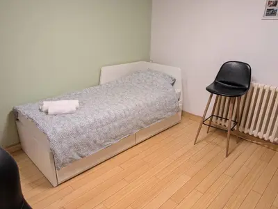 a bedroom with a bed and a black chair at Apartman Jevremov Kutak in Belgrade