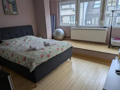 a bedroom with a bed and a large window at Apartman Jevremov Kutak in Belgrade