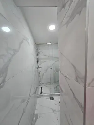 a bathroom with white marble walls and a shower at White Queen in Bukorovac