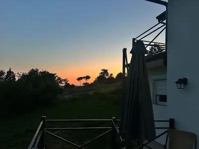 a sunset from the outside of a house with an umbrella at Mali Raj in Mala Ivanča