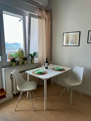 a white table and chairs in a room with a window at City Heart Studio, City Center in Belgrade