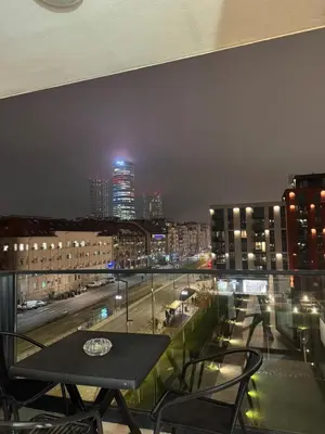 a table on a balcony with a view of a city at night at BW Premium Apartment Wolf-free parking in Belgrade