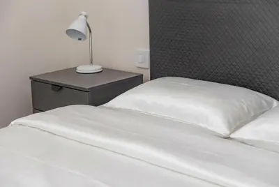 a bed with white sheets and a lamp on a night stand at BW Premium Apartment Wolf-free parking in Belgrade