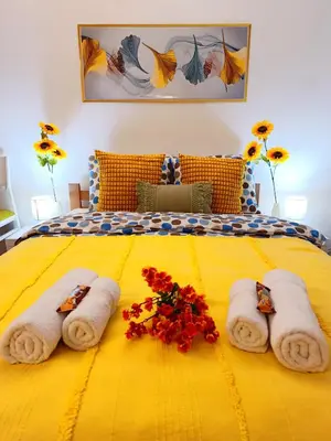 a yellow bed with towels and flowers on it at Urban Garden Apartments - Sunflower 2 in Belgrade