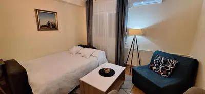 a small bedroom with a bed and a chair at Retiro Apartman in Belgrade