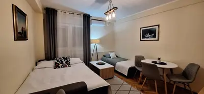 a room with two beds and a table and chairs at Retiro Apartman in Belgrade