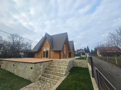 a log cabin with a slate roof and a stone wall at Kuće za odmor Banstolija - Fruška Gora in Čortanovci