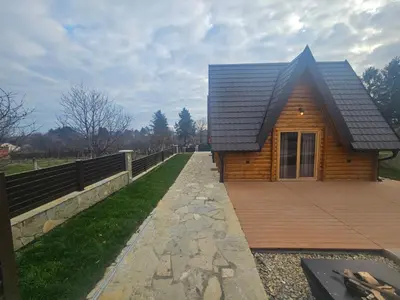a log cabin with a walkway leading to a house at Kuće za odmor Banstolija - Fruška Gora in Čortanovci