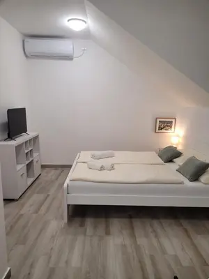 a white bedroom with a bed and a tv at Beosan in Belgrade