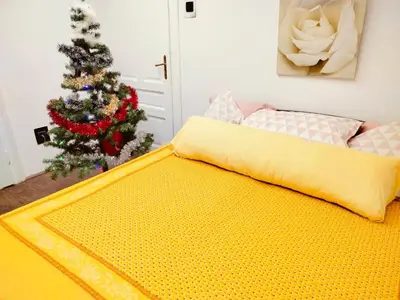 a bed with a yellow blanket next to a christmas tree at Moulin ROSE in Belgrade