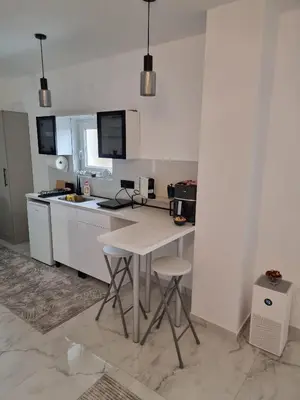a kitchen with white cabinets and a table with two stools at Infinity in Belgrade
