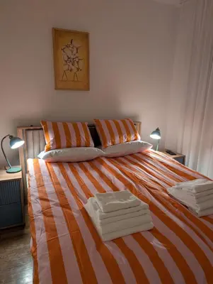 a bed with orange and white striped sheets and pillows at Nova Vracar - Luxury Apartment & Private Parking in Belgrade
