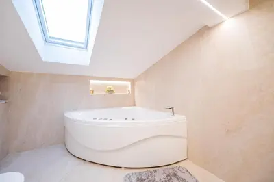 a bathroom with a white tub and a skylight at Stella Di Notte City Center Studios in Belgrade