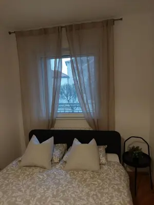 a bed with pillows in front of a window at Jana's in Belgrade