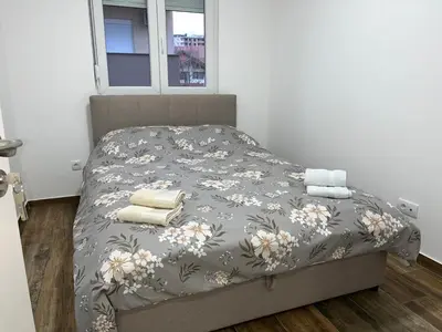 a bed with a gray comforter with towels on it at Mimura 3 in Belgrade