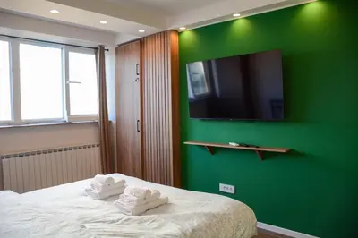 a bedroom with a green wall and a bed with towels at LUX apartment 15 min walk to Knez Mihajlova in Belgrade