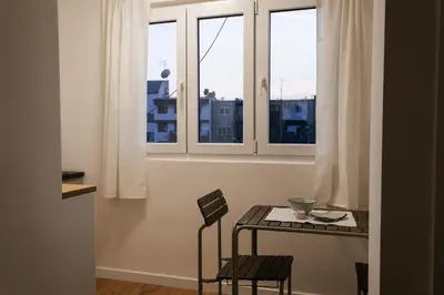 a table and chairs in a room with two windows at Astor Wellness apartman in Belgrade