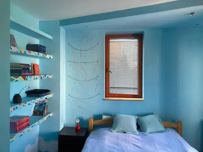 a blue bedroom with a bed and a window at Artists Apartment in Beograd