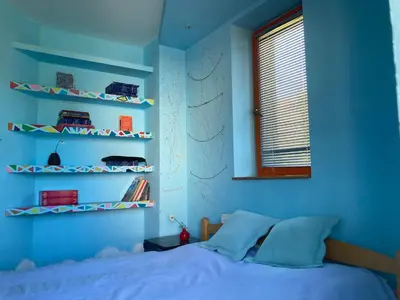 a bedroom with blue walls and a bed and shelves at Artists Apartment in Beograd