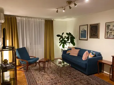 a living room with a blue couch and two chairs at Belgrade Retro City Center Apt in Belgrade