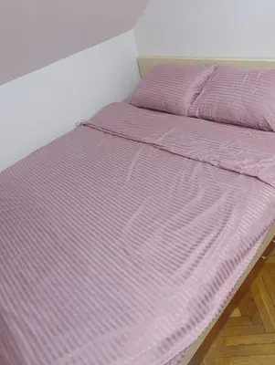 a bed with a purple comforter in a room at Apartman 32 in Inđija