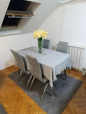a dining room table with chairs and a vase of flowers at Apartman 32 in Inđija