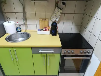 a small kitchen with green cabinets and a sink at Apartman 32 in Inđija