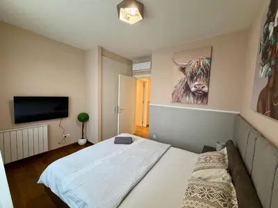 a bedroom with a bed and a painting of a cow at The Gates Apartments Belgrade Waterfront in Belgrade