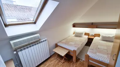 an attic room with two beds and a radiator at Apartment Akacija Gardens in Belgrade