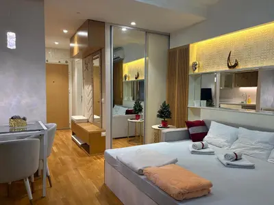 a bedroom with a bed and a desk and a kitchen at Lunalux BW Apartments in Belgrade