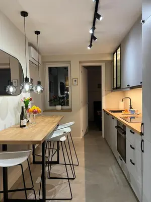 a kitchen with a wooden table and white cabinets at Sovica- Taš in Belgrade