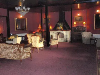 a living room with a fireplace and a room with chairs at Hostel Otard in Belgrade