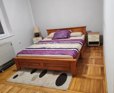 a bedroom with a bed with a purple pillow and a rug at Signorina in Smederevo