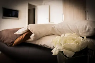 a bed with white sheets and a white flower on a table at Apartment Admiral in Belgrade