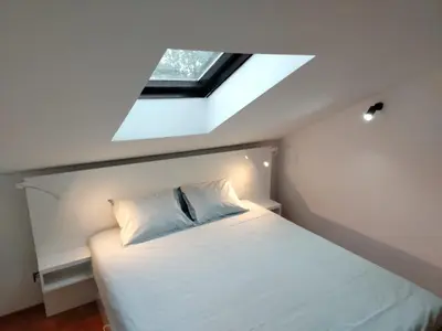 a bedroom with a white bed with a skylight at LoLo apartment Belgrade in Beograd