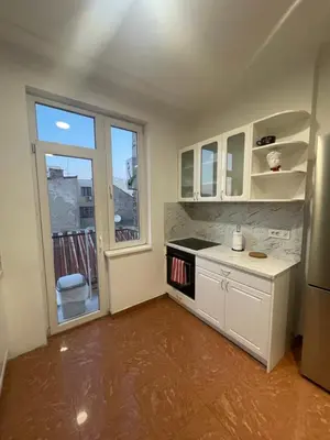a kitchen with white cabinets and a large window at New Luxury Strict Center Apartment in Belgrade